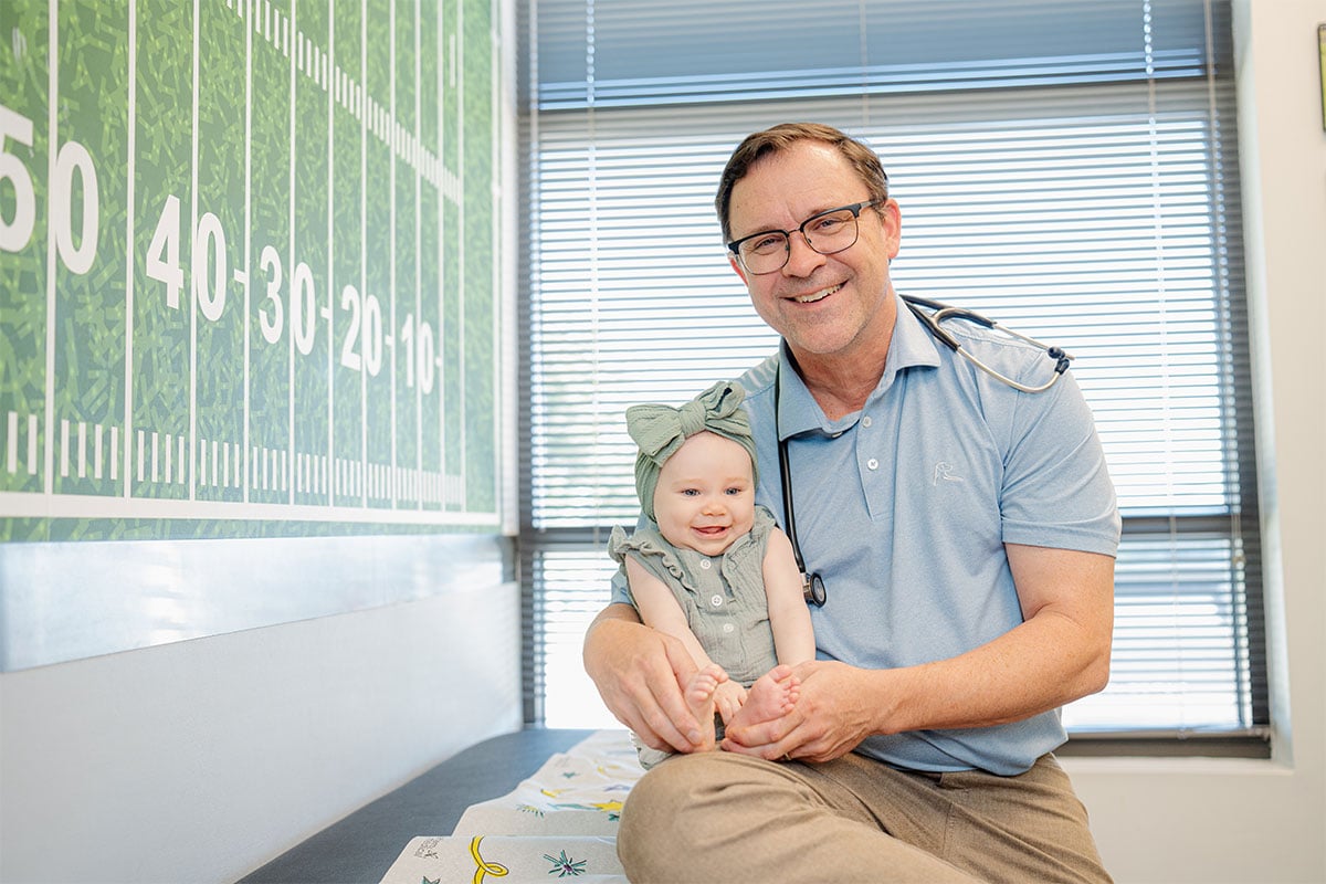 Pediatric physician holding a baby at a primary care office in Little Elm, Texas