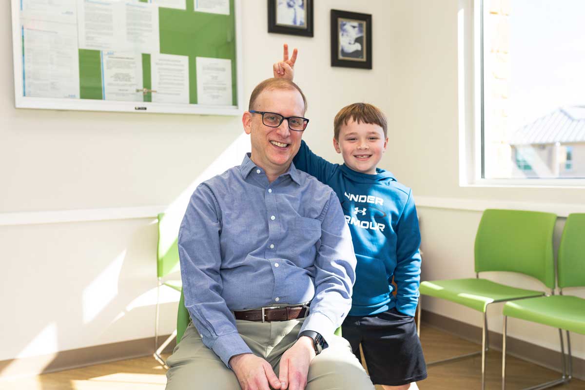 Dr. Seth Kaplan getting bunny ears from boy in blue shirt