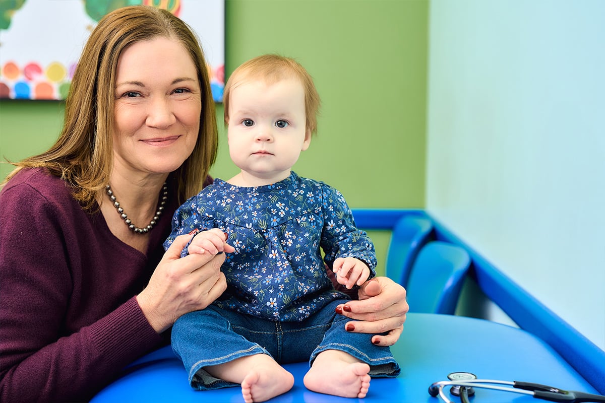 A pediatrician holding a baby in the exam room of the pediatric office
