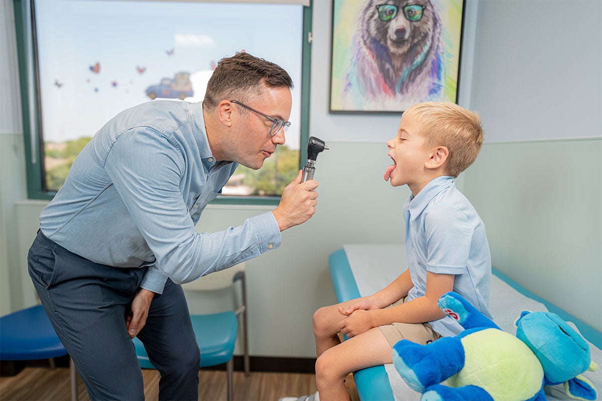 Pediatric physician examining a child’s throat and mouth at a pediatric primary care office in Plano, Texas