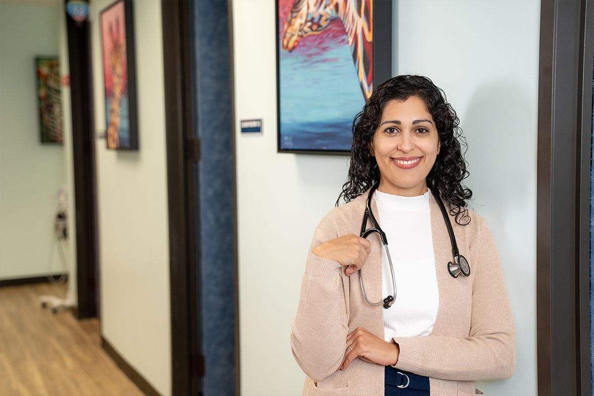 Pediatric physician smiling while wearing a stethoscope at a pediatric primary care office