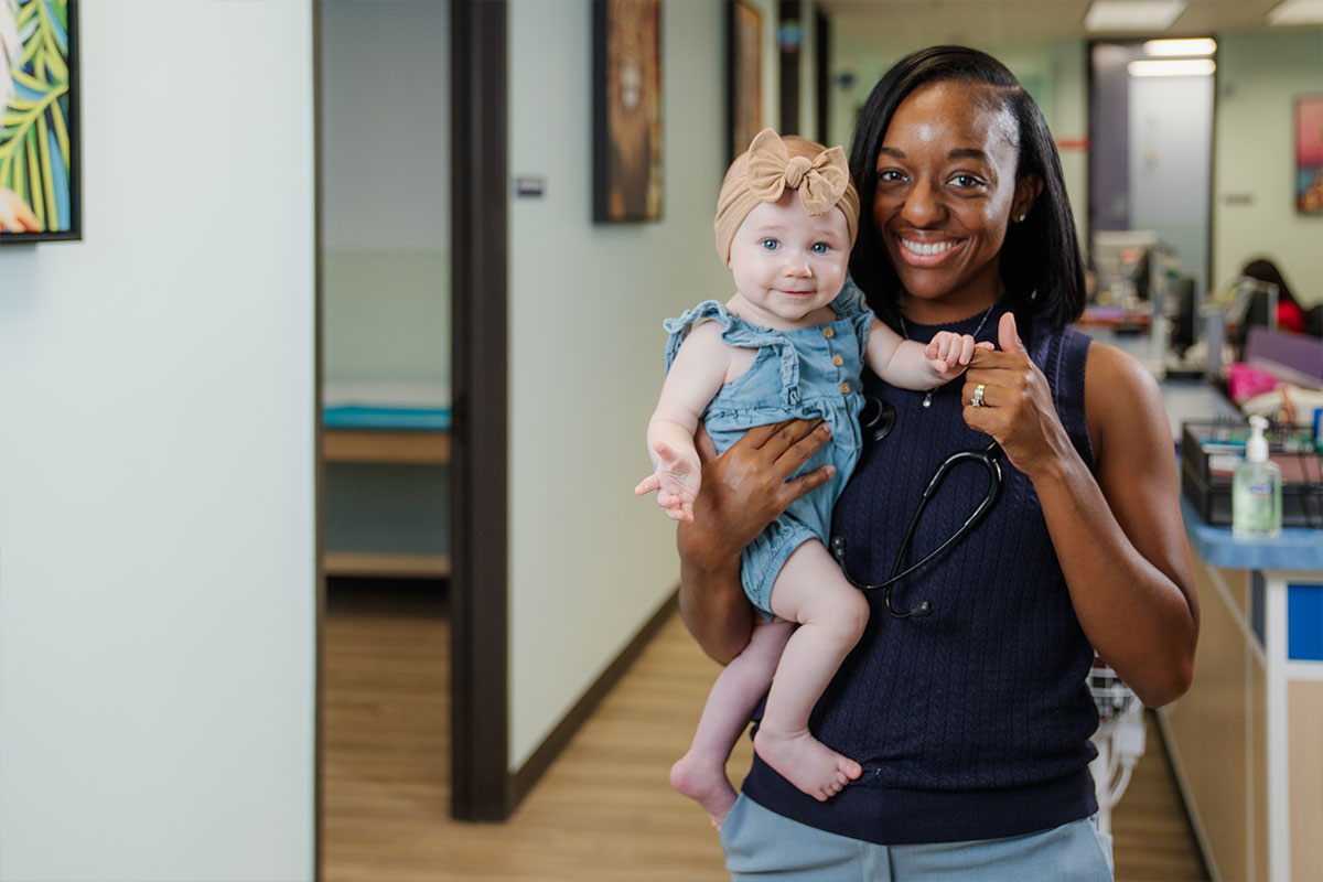 Pediatric physician holding a baby after a wellness check at a pediatric primary care office in Frisco, Texas