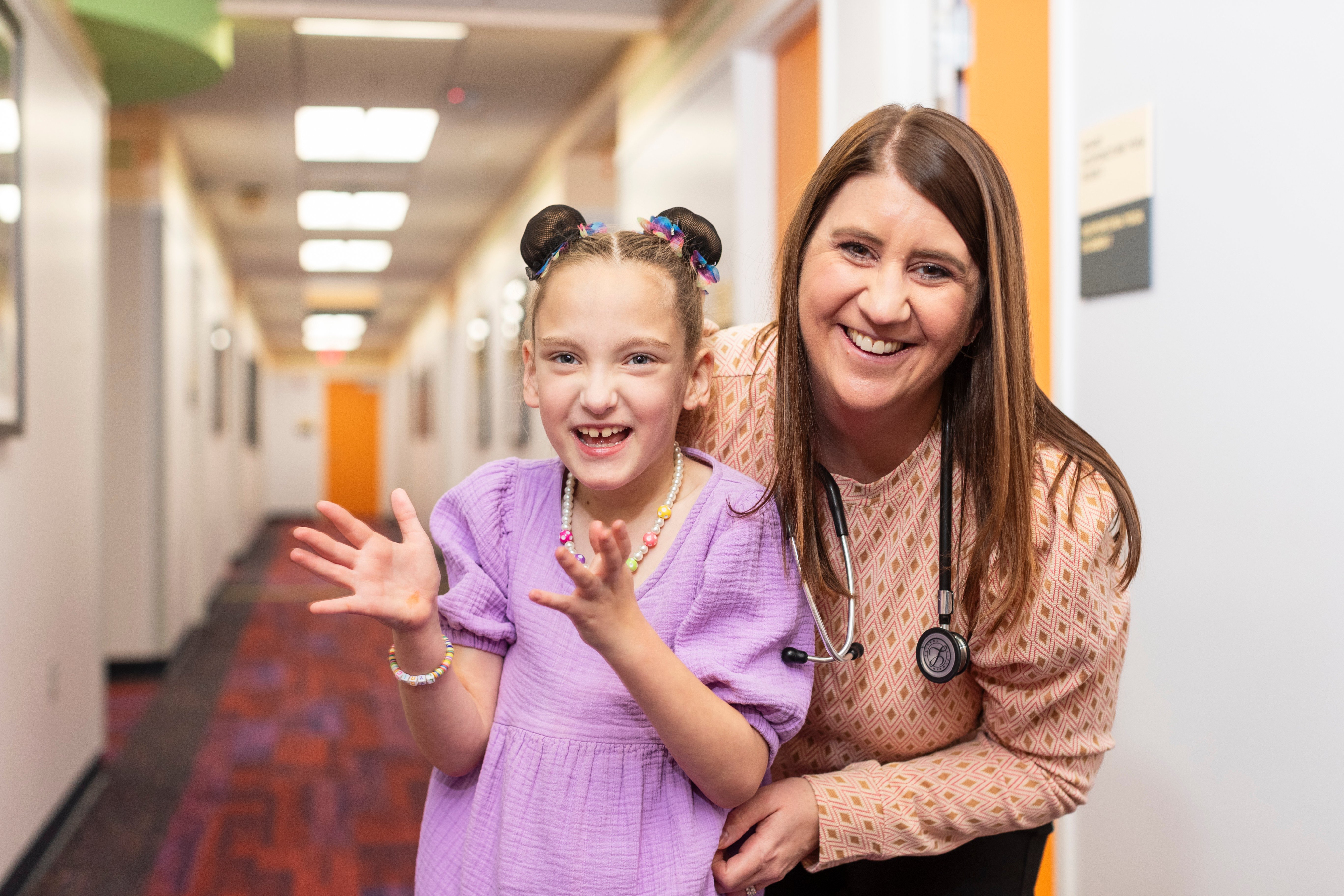Young girl in a purple dress and doctor with a stethoscope both smiling